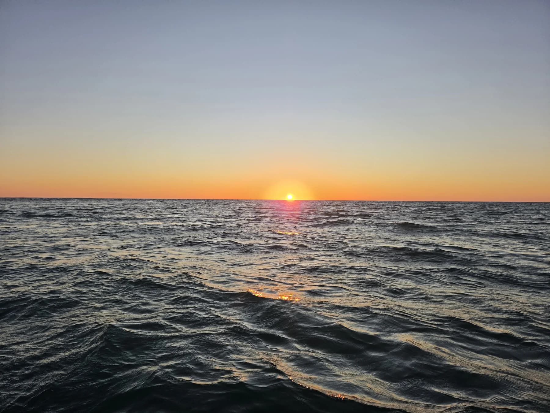 Warm golden light stretching across the water beneath an open coastal sky
